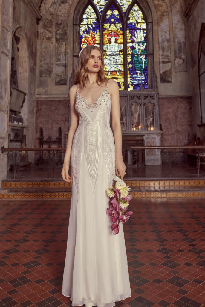 A model wearing a column dress with a v-neck and art deco style embellishments  