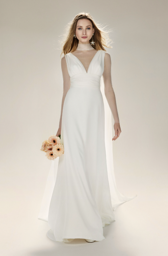 Model wearing greek-style column wedding dress with a deep-v neck, material clustered around the waist and an a-line skirt